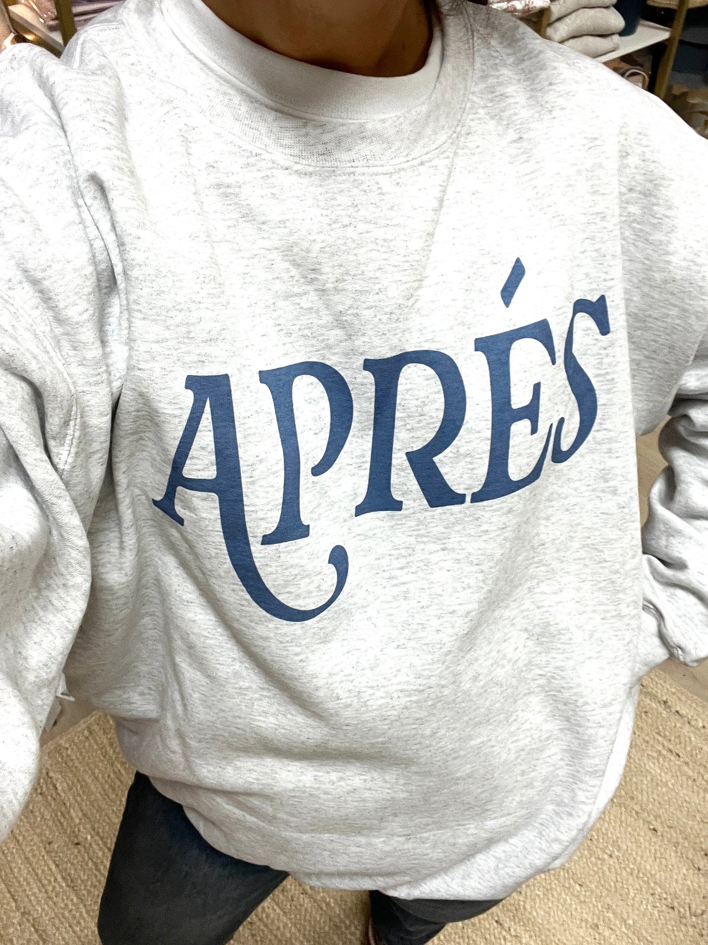 Gray sweatshirt with 'APRéS' printed in blue on a neutral background