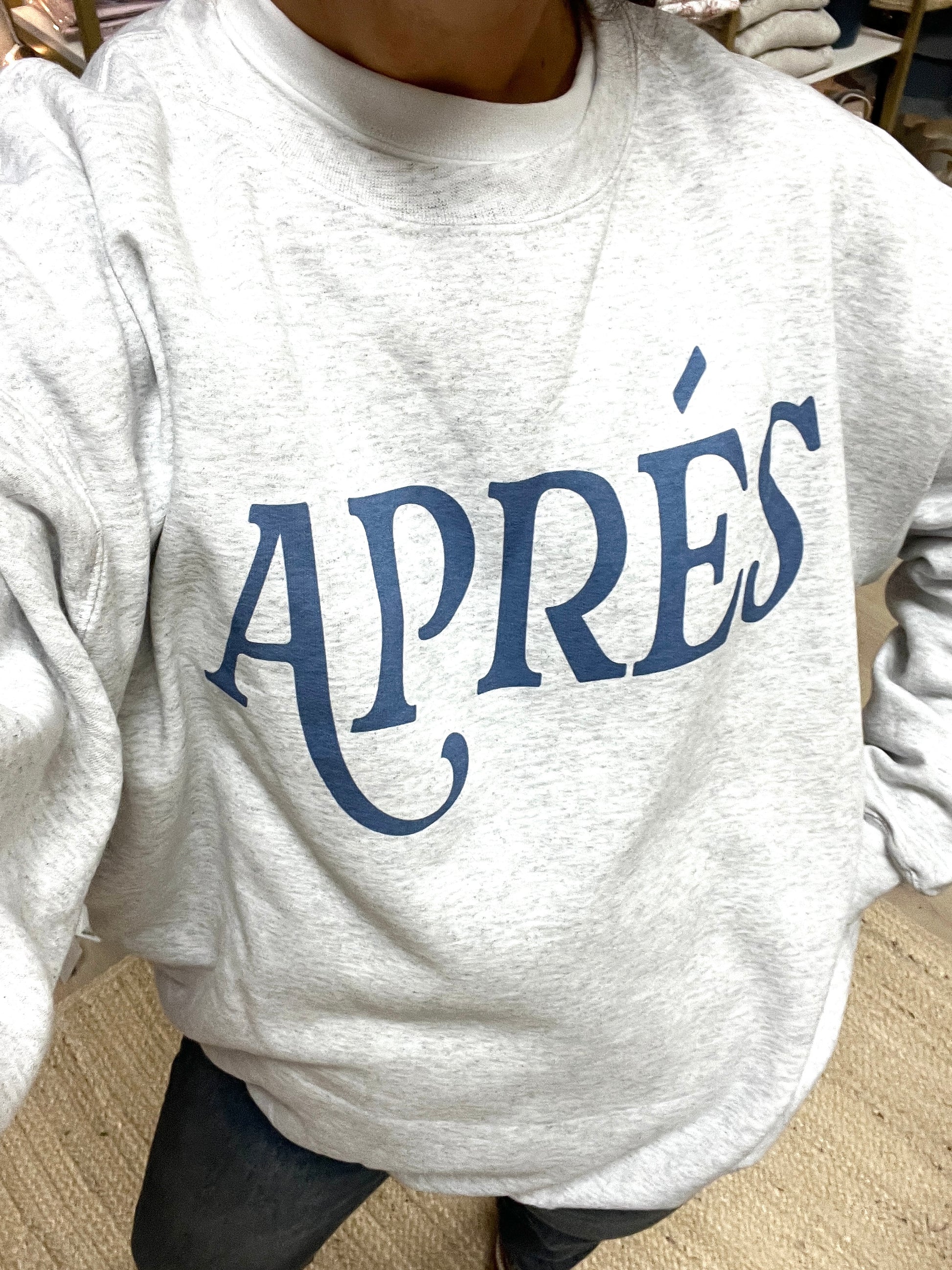 Gray sweatshirt with 'APRéS' printed in blue on a neutral background