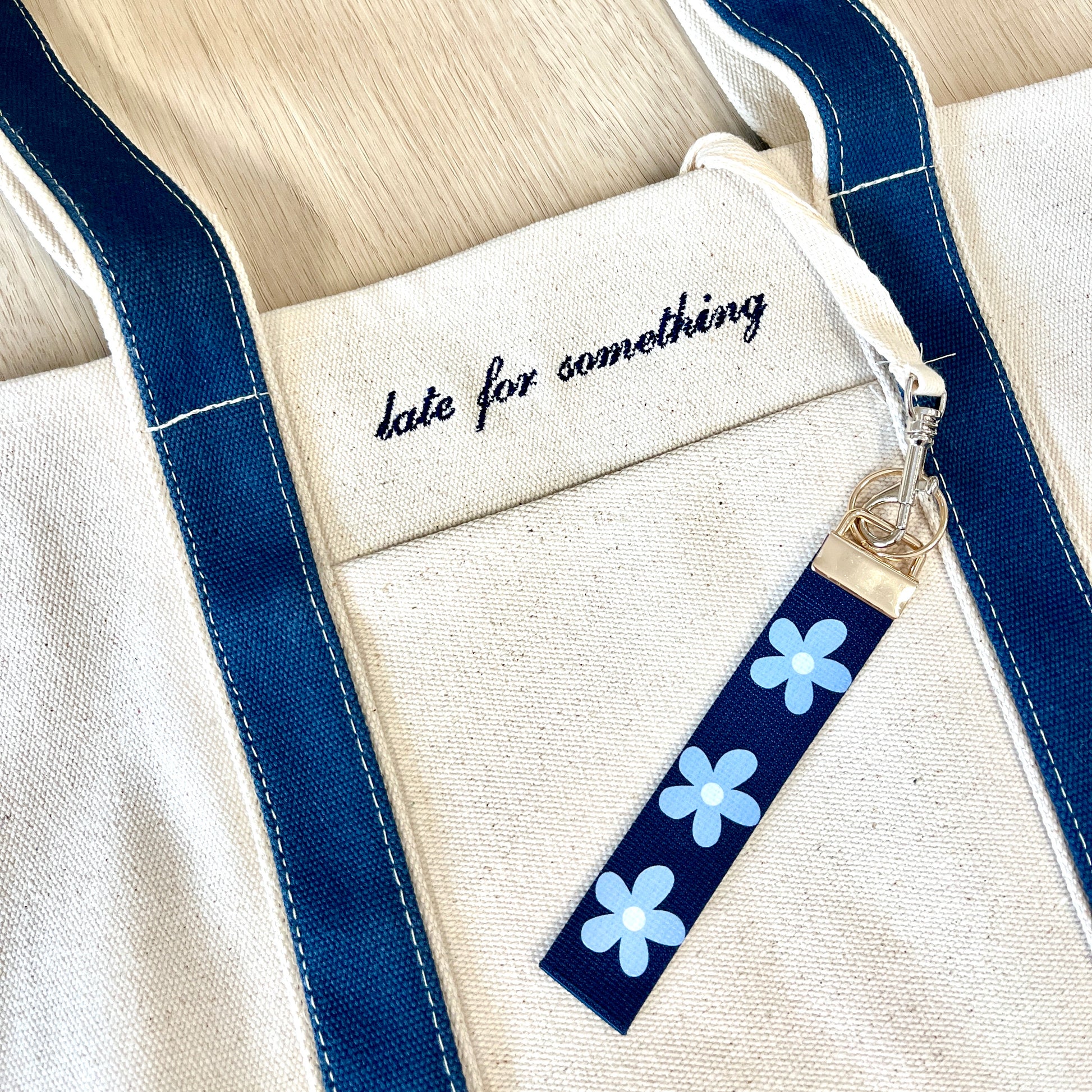 Keychain with blue flowers attached to a bag with text 'date for something'.