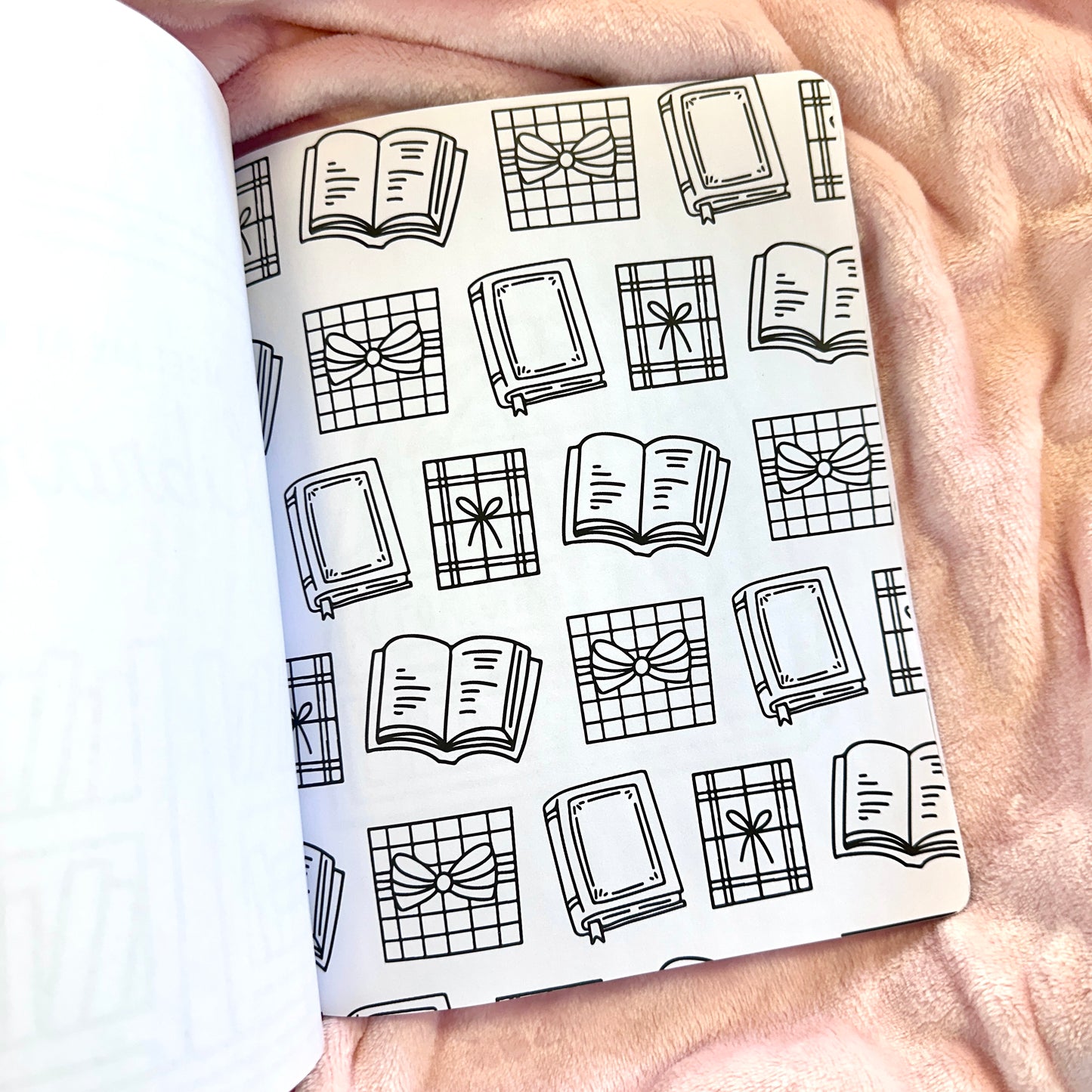 Notebook with a black and white pattern of books and bows held by a person.
