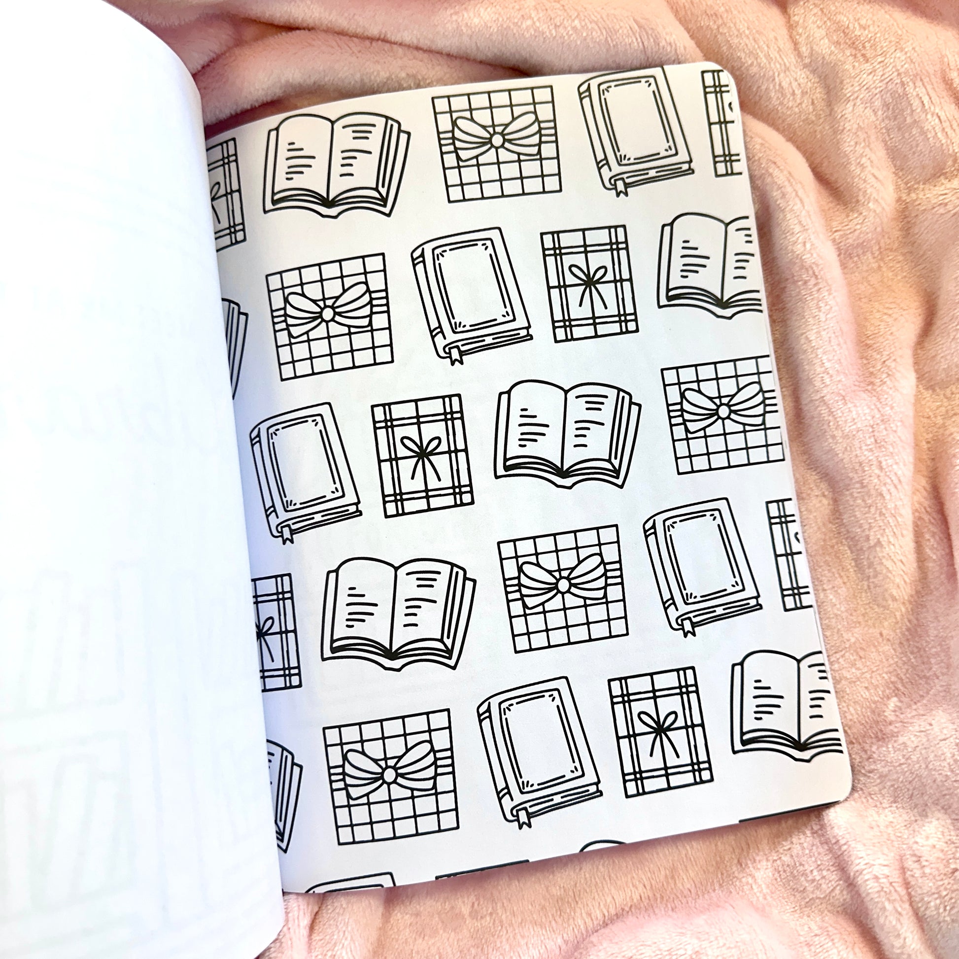 Notebook with a black and white pattern of books and bows held by a person.