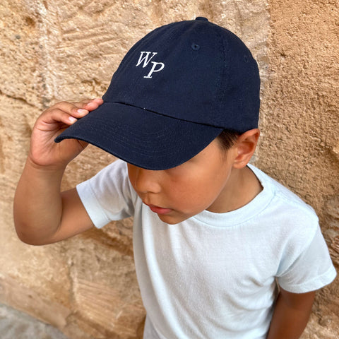 Young boy wearing a monogrammed baseball cap in navy