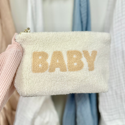 White fluffy pouch with 'BABY' text in gold on a blurred background