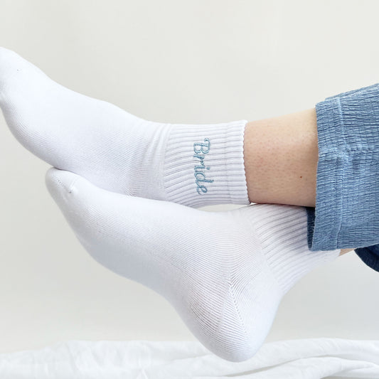 woman wearing blue pajama pants and white ankle crew socks with custom bride powder blue embroidered design