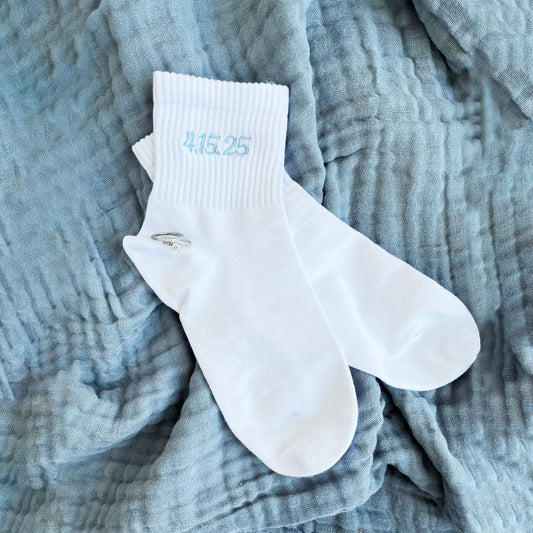 white ankle crew socks with custom date embroidered in a powder blue thread.