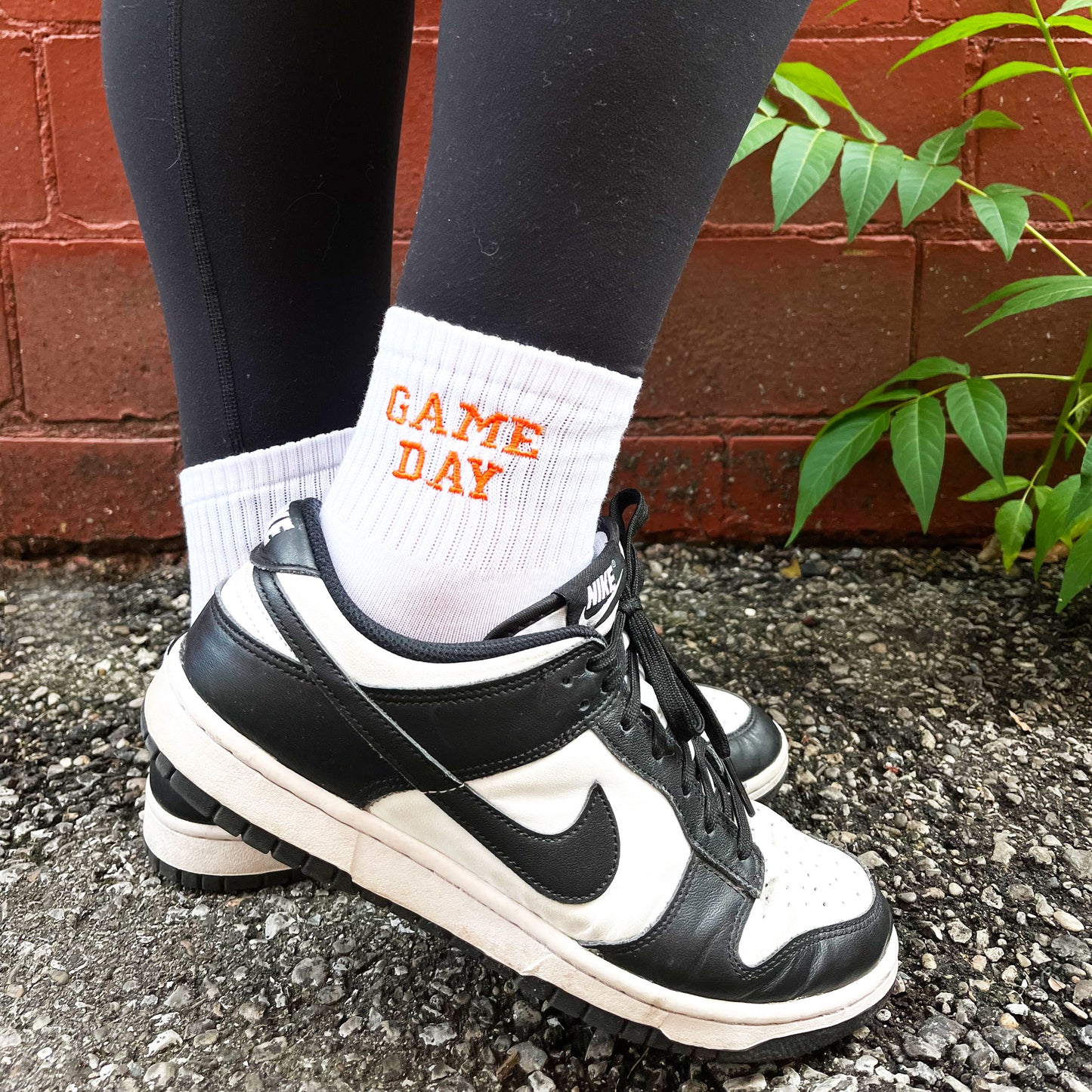 woman wearing black and white Nikes with custom embroidered game day ankle crew socks