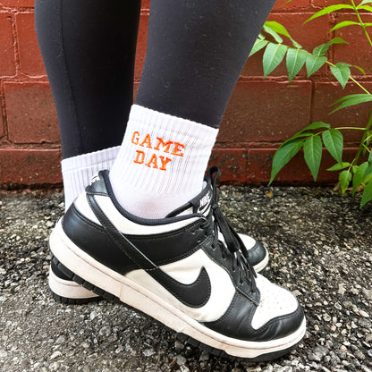 woman wearing black and white Nikes with custom embroidered game day ankle crew socks