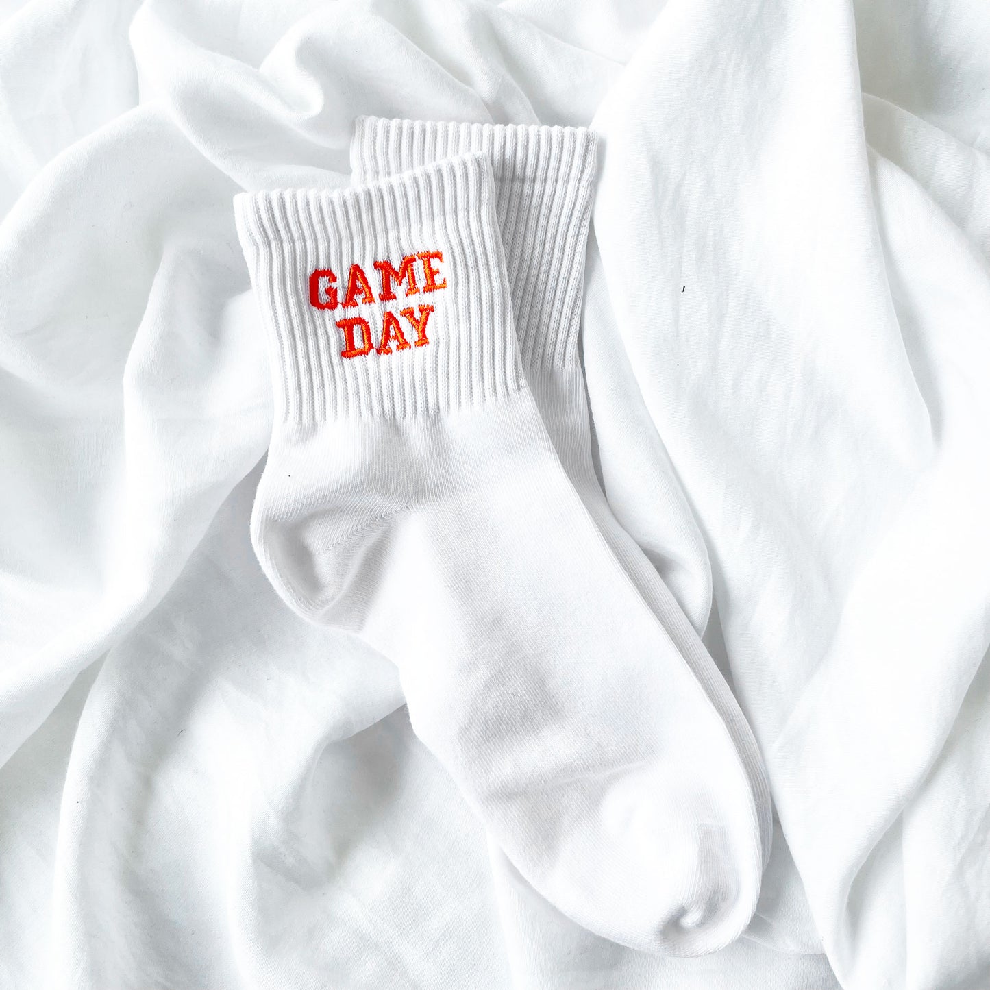 white ankle crew socks with custom game day embroidered design in an orange thread and collegiate font.