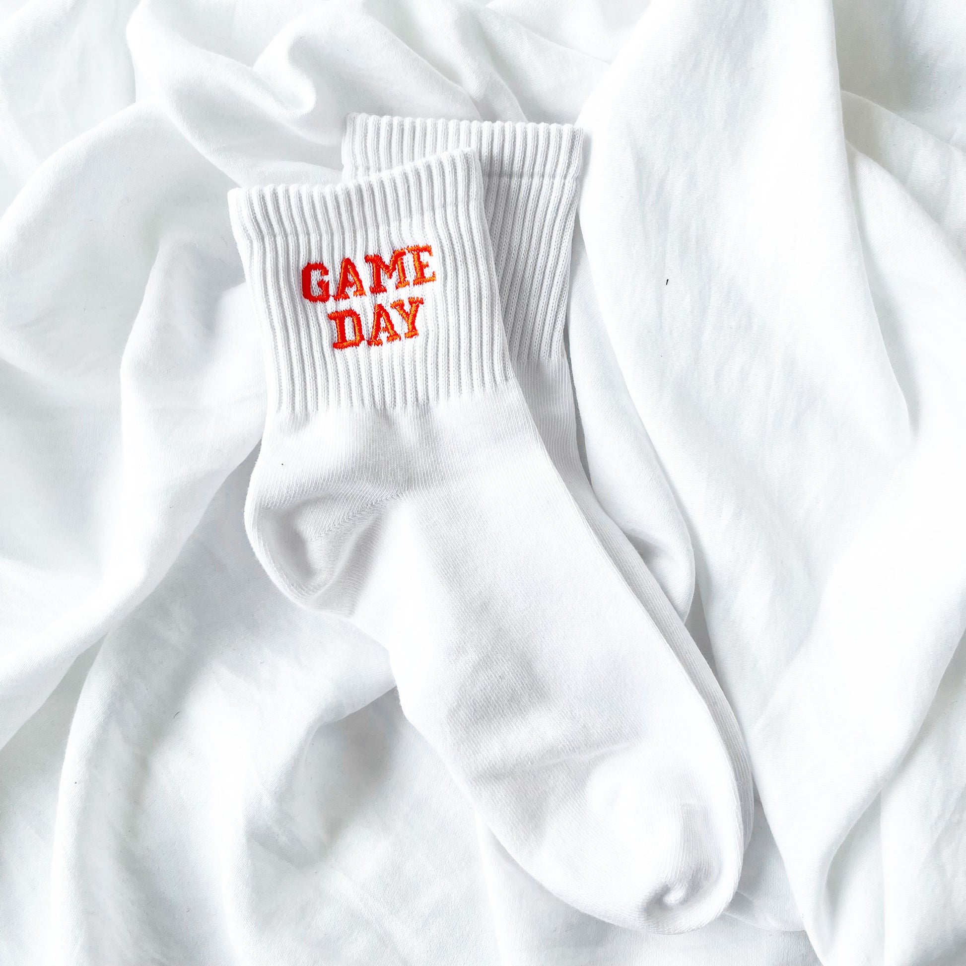 white ankle crew socks with custom game day embroidered design in an orange thread and collegiate font.