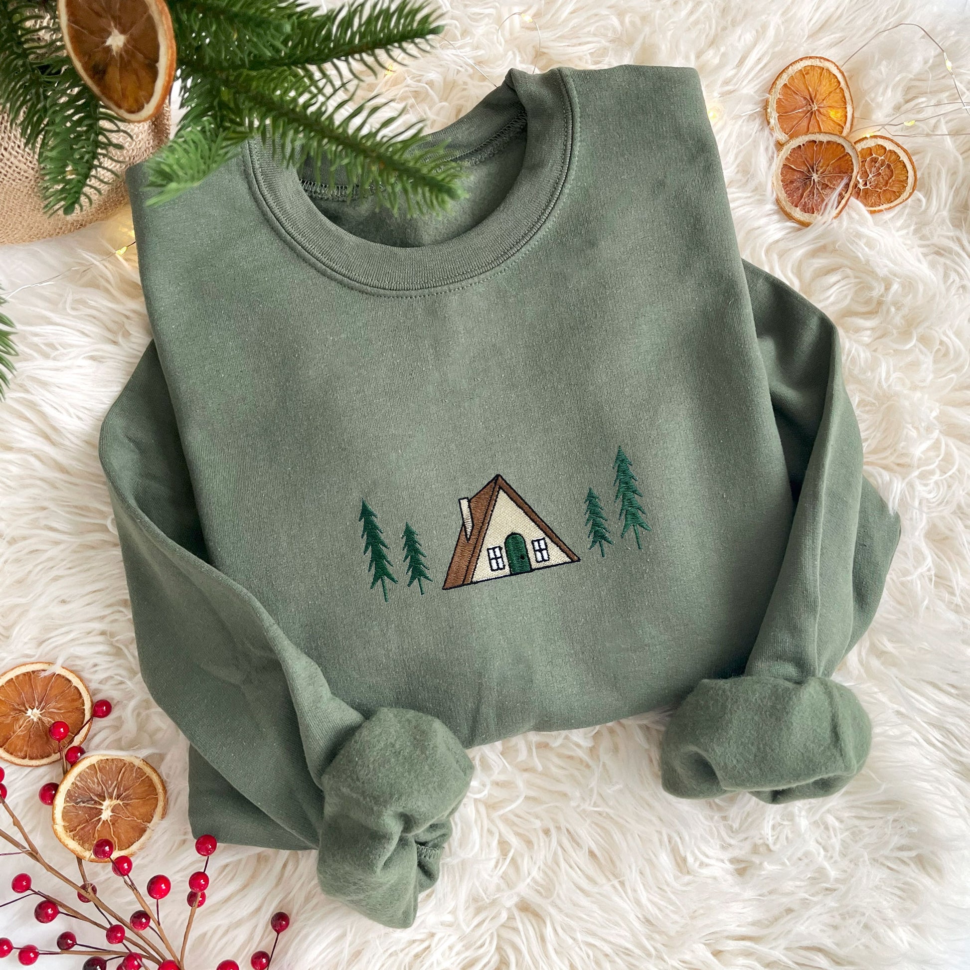 flat lay of a military green crewneck sweatshirt with embroidered a frame cabin design across the chest