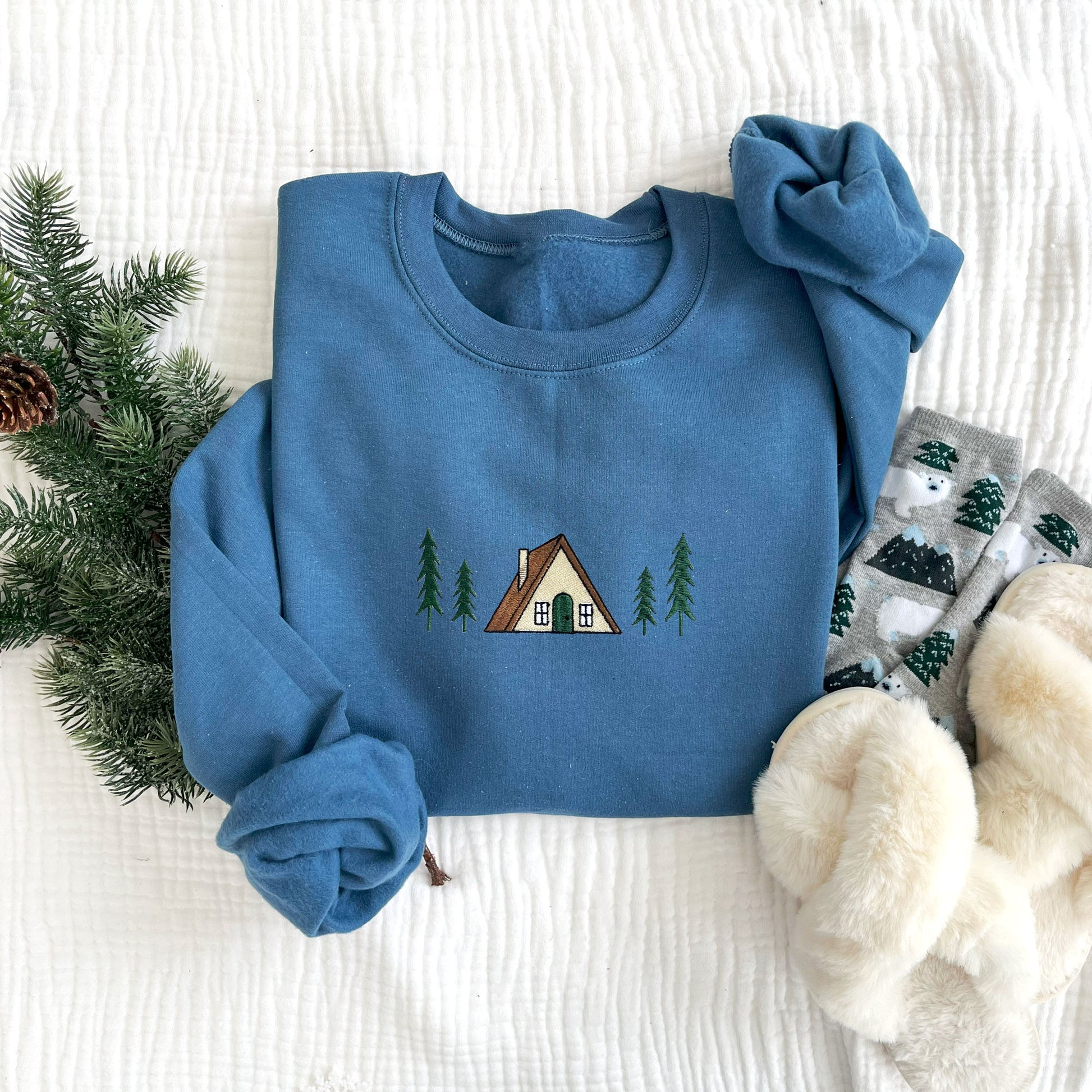 flat lay of an indigo crewneck sweatshirt with embroidered a frame cabin design across the chest