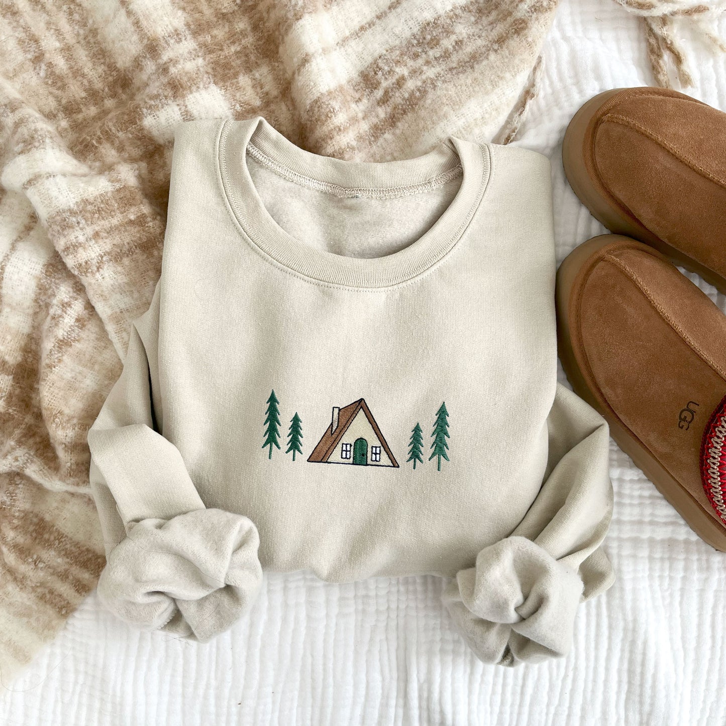 flat lay of a sand crewneck sweatshirt with embroidered a frame cabin design across the chest