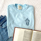 chambray comfort colors t-shirt with a floral embroidered cross in french blue thread and a pair of jean shorts styled with a bible