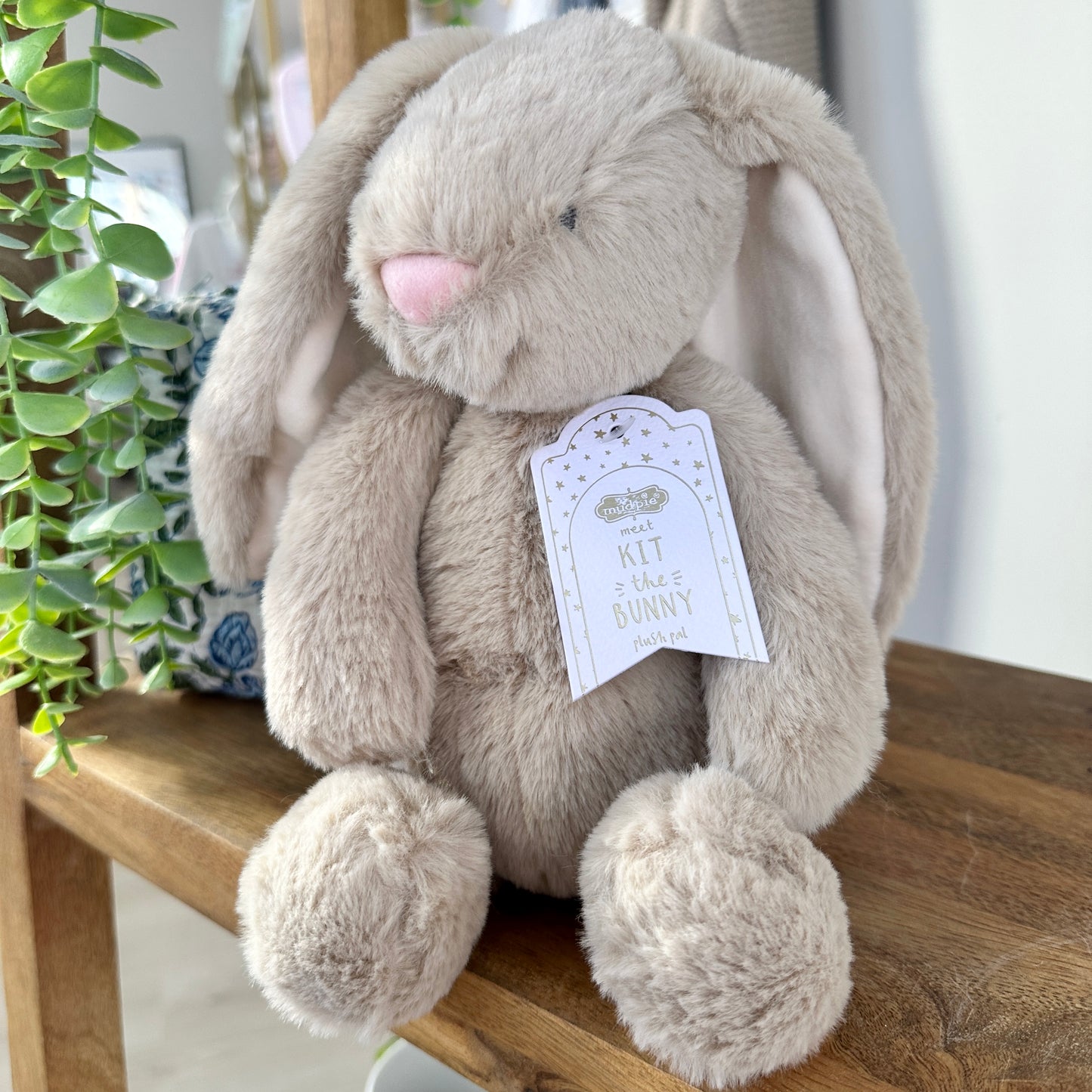 Plush bunny toy with a tag on a wooden surface