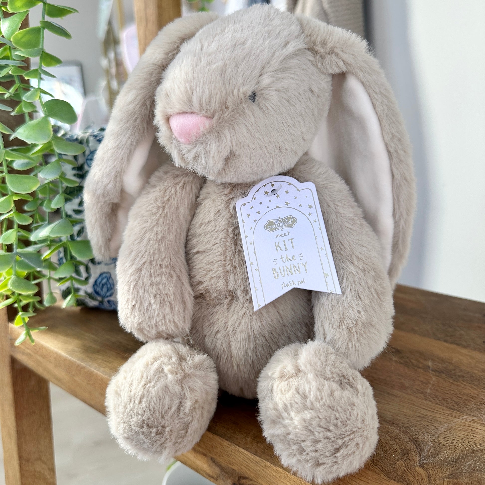 Plush bunny toy with a tag on a wooden surface