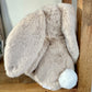 Plush bunny toy with a visible brand label on a wooden surface