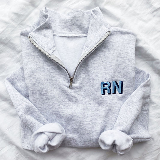 light heather grey quarter zip sweatshirt with custom shadow block nurse credentials embroidered on the left chest