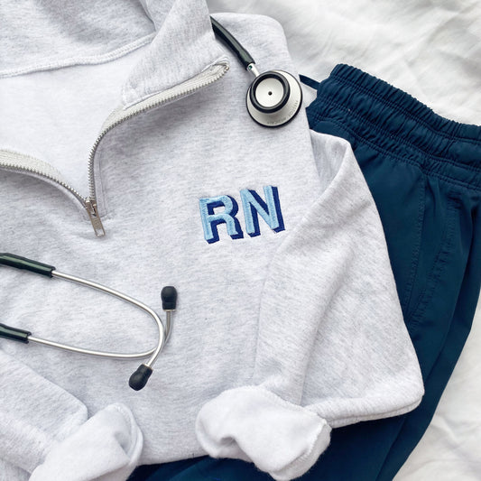 ash grey quarter zip sweatshirt with custom shadow block nurse credentials embroidered on the left chest