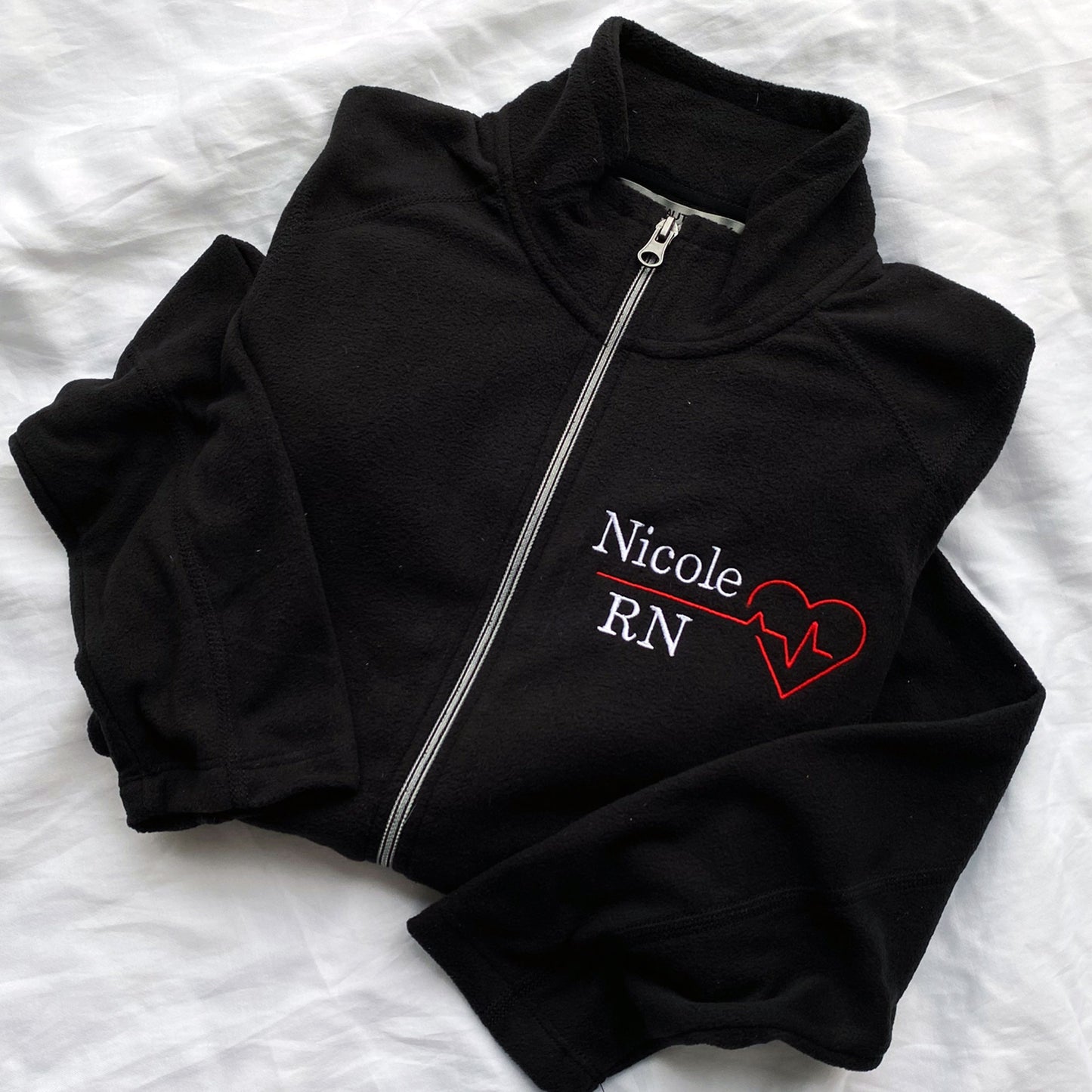 Black lightweight fleece full zip with custom name, credential, and heartbeat embroidered design on the left chest. 