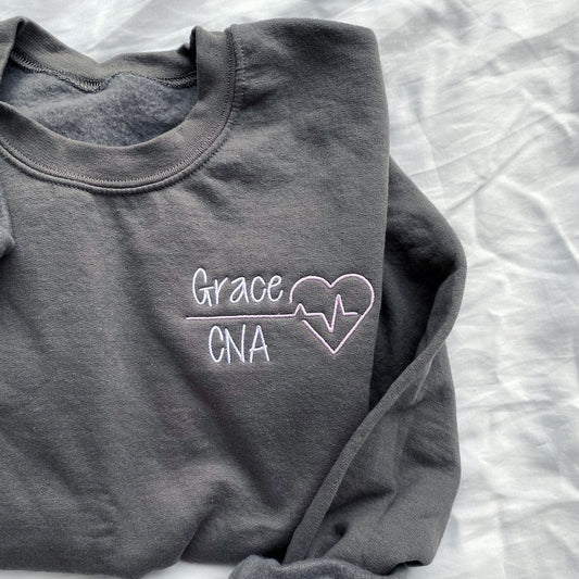 dark grey sweatshirt with name/credentials and heartbeat embroidered design for nurses