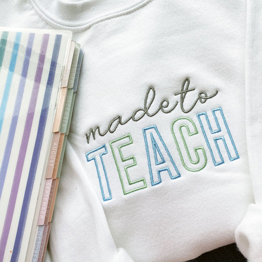 close up of a made to teach embroidered design on a white crewneck sweatshirt