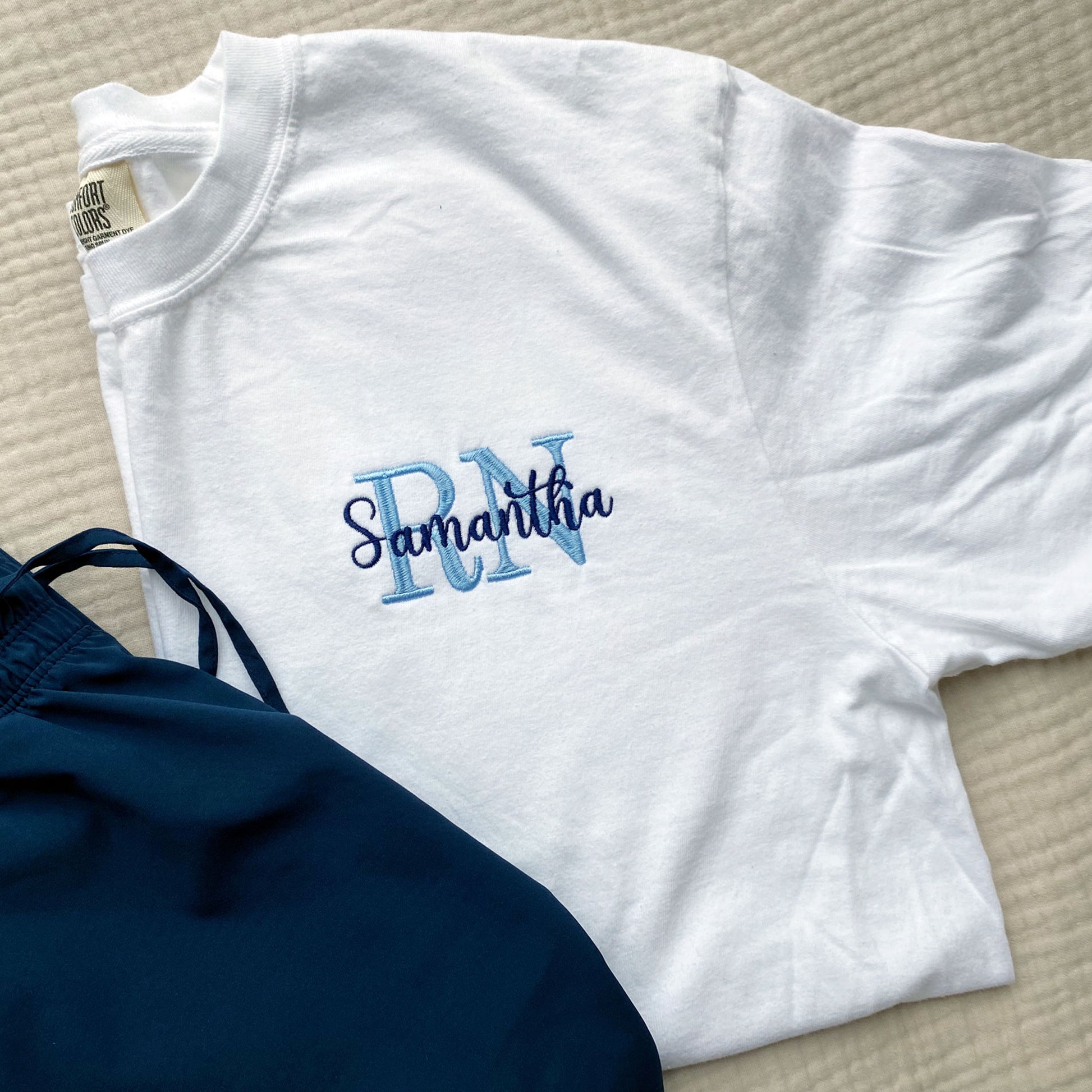 white comfort colors tee with a custom nurse embroidered design featuring credentials and name