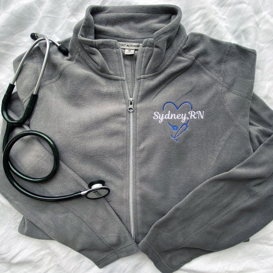light grey full zip fleece jacket with a personalized heart stethoscope and name embroidered on the upper left chest