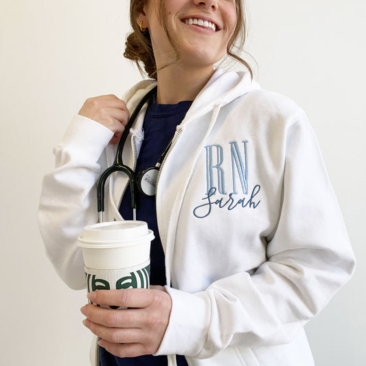 nurse wearing a white full zip jacket with rn and name embroidered on the left chest