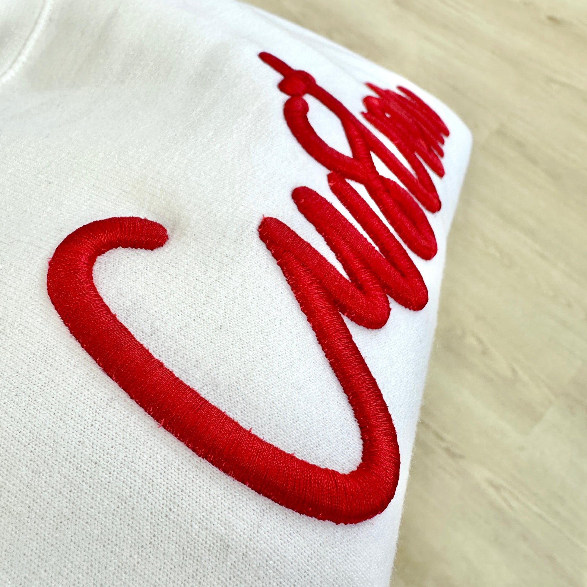 White fabric with red embroidered lettering on a wooden surface