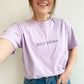 young woman wearing an orchid comfort colors t-shirt with custom all caps minimal name embroidery in smoky orchid thread