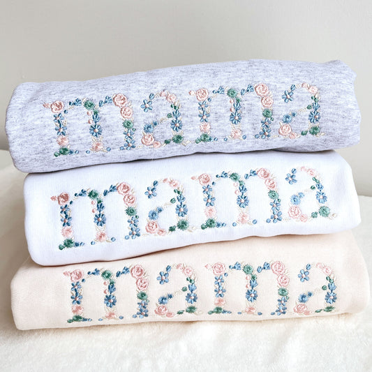 stack of crewneck sweatshirts with custom floral mama embroidered design in light pastel threads.