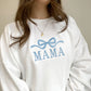 close up of a young woman wearing a white crewneck sweatshirt with embroidered large bow and all caps mama design in baby blue thread across the chest