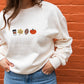 close up of a woman wearing  a sweet cream crewneck sweatshirt with embroidered coffee, leaf,  ootball, and pumpkin design across the chest