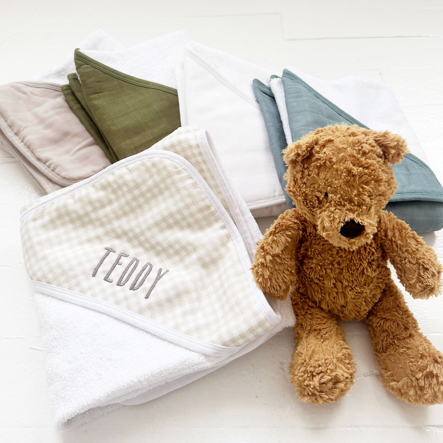 stack of muslin baby hooded bath towels and a teddy bear