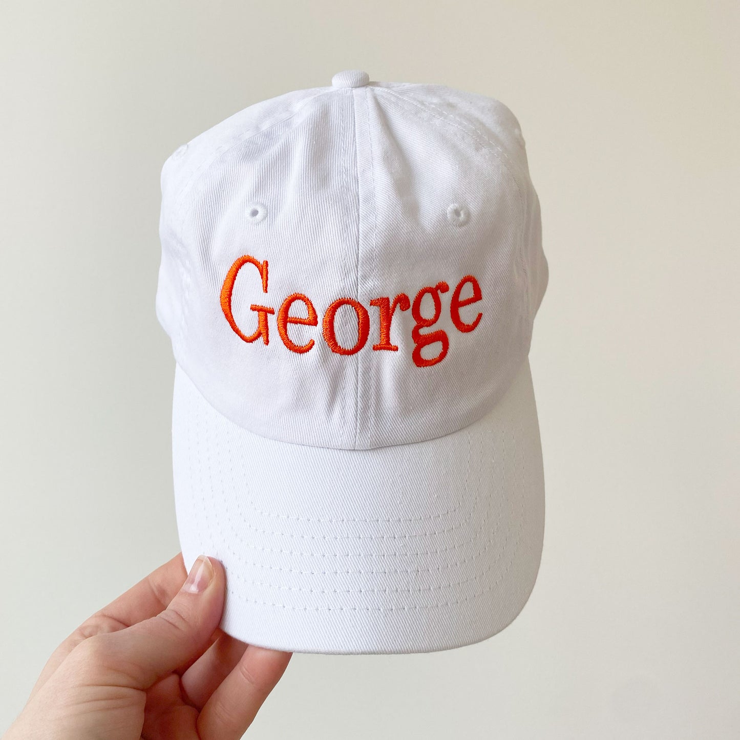 youth white baseball hat with George embroidered in orange thread