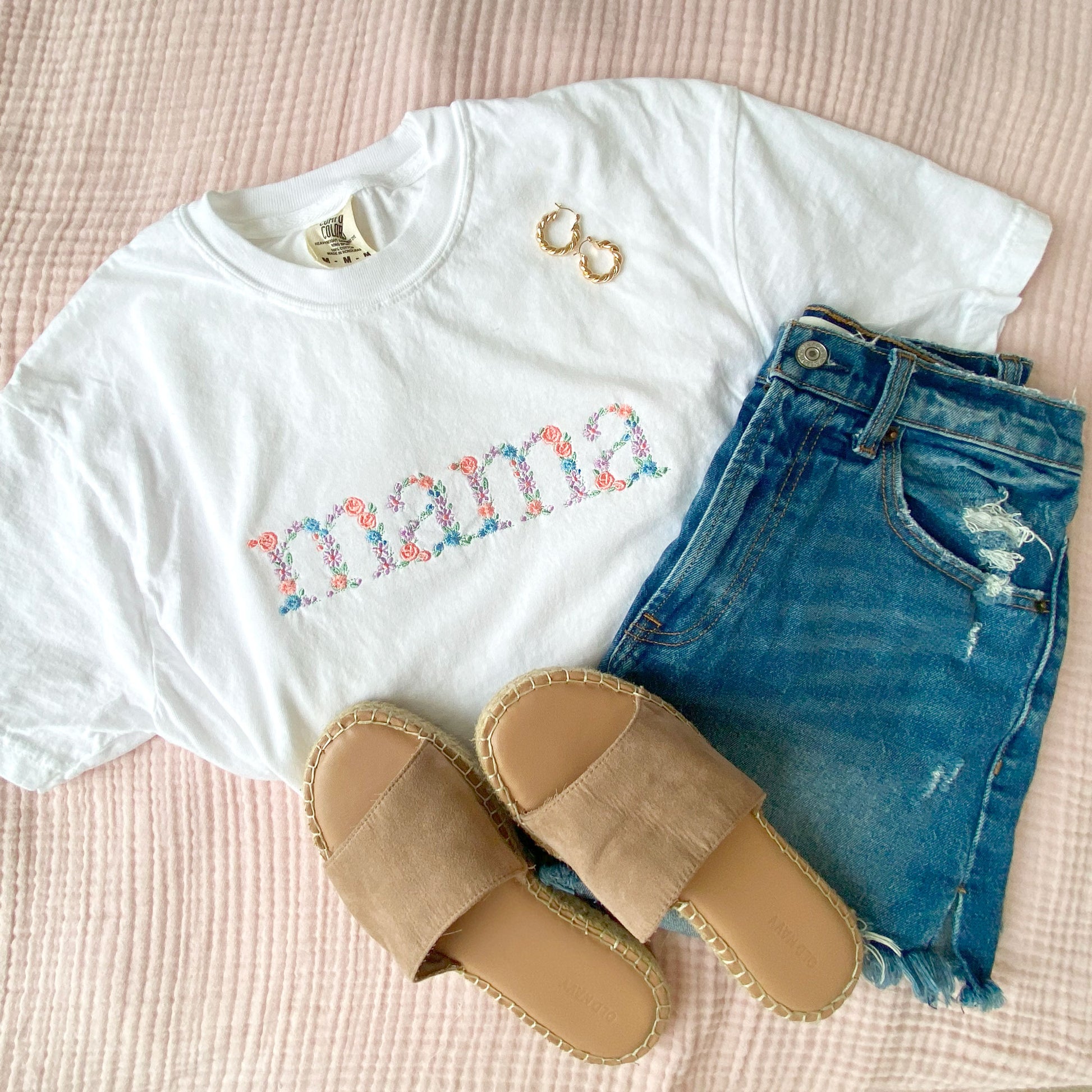 white comfort colors t-shirt with embroidered mama floral design paired with sandals and jean shorts