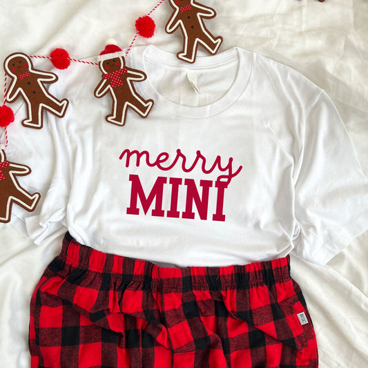 youth white bella and canvas t-shirt with buffalo plaid pajama pants. printed on the tee says merry mini in red ink