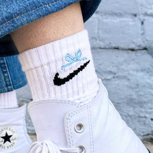 close up of a mini bow embroidered on a pair of nike socks