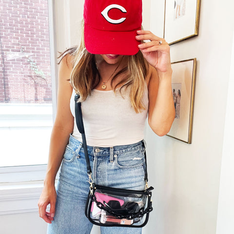 girl dressed to go to a baseball game wearing a clear crossbody bag with a double strap and black trim