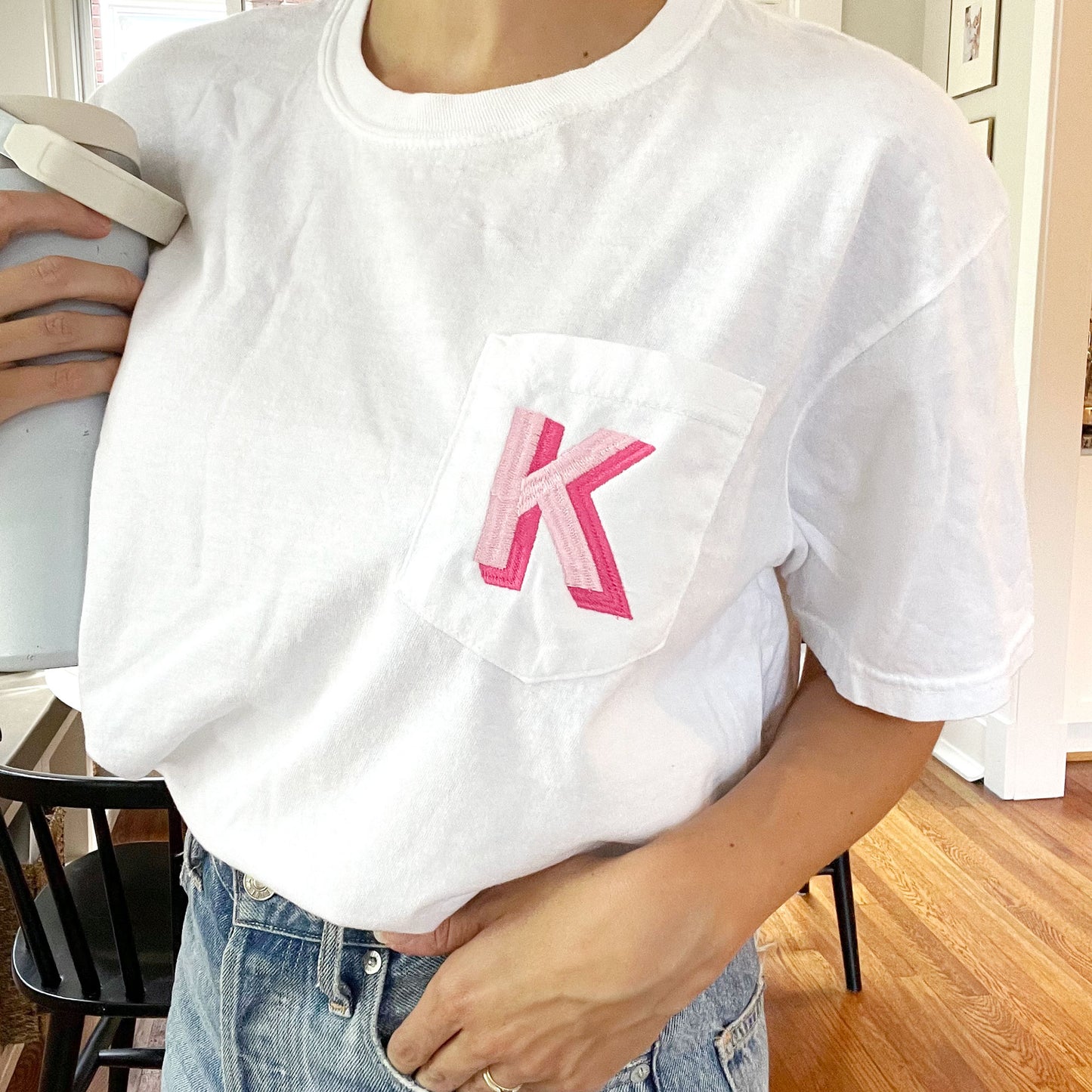 girl wearing white tee with pink shadow block initial embroidered on the pocket