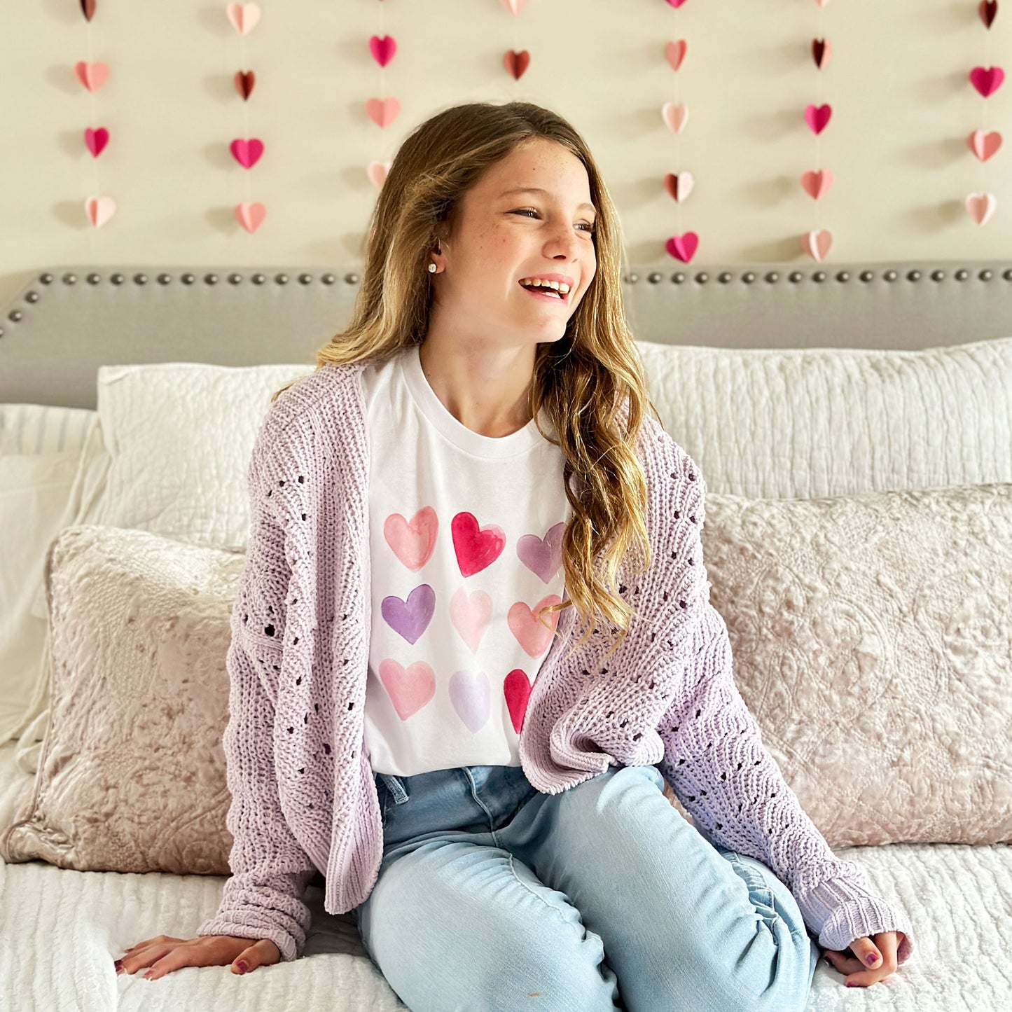 Little girl laughing, wearing a valentine's day themed tee with a colorful watercolor heart design