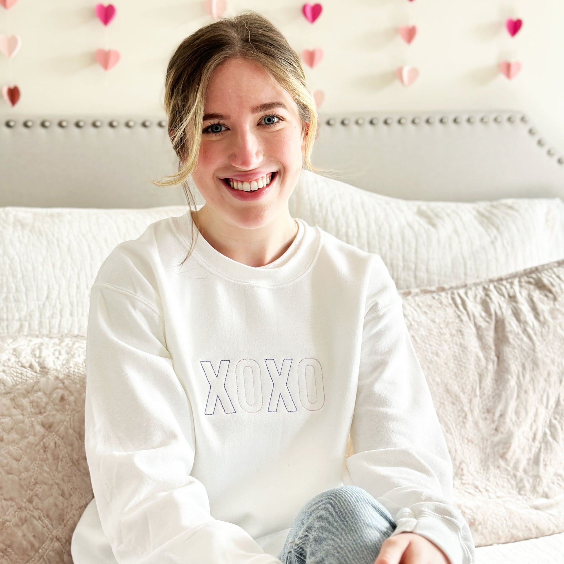young woman modeling a valentines purple xoxo embroidered white crewneck sweatshirt