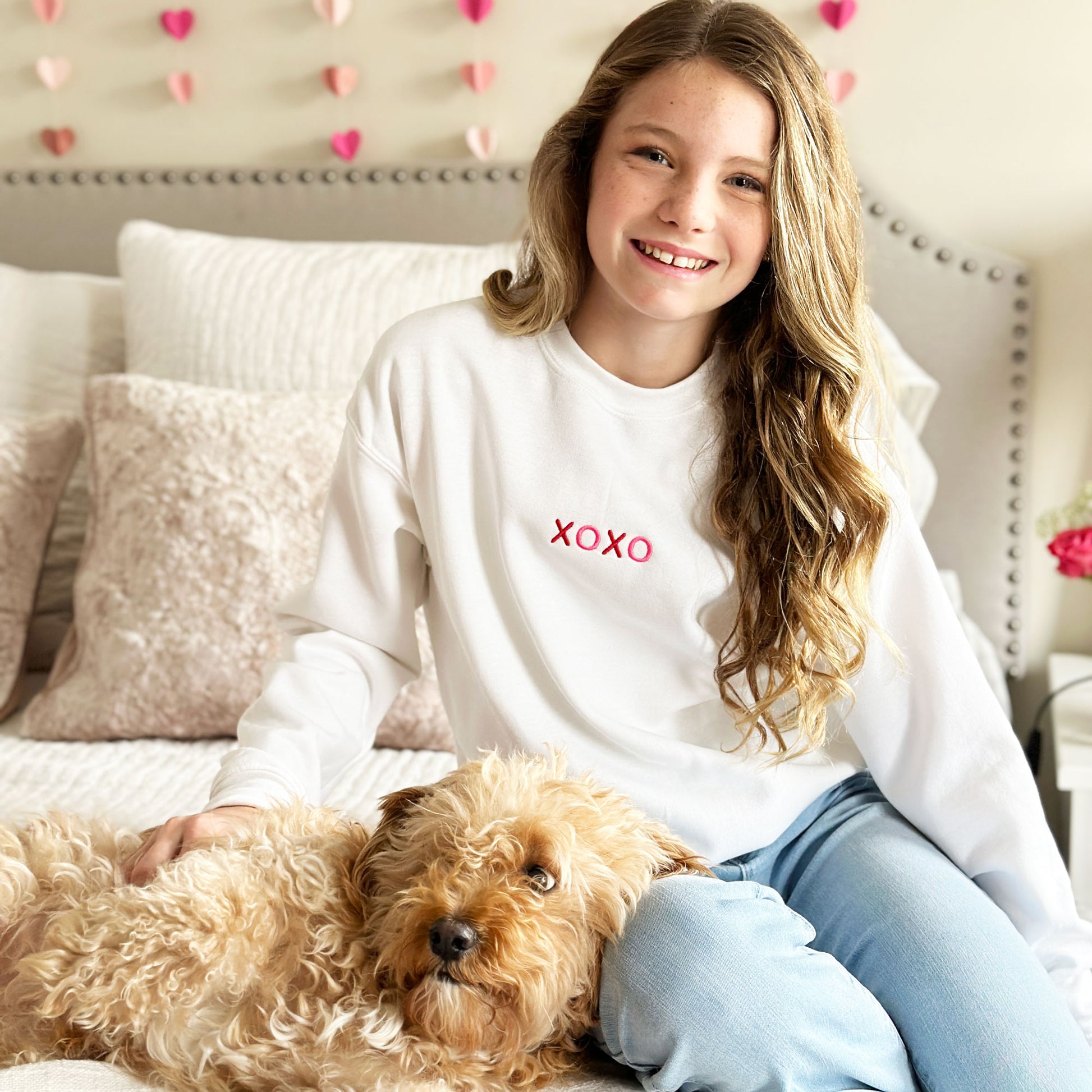 girl with her dog wearing a cute an festive white sweatshirt with xoxo embroidered on the front