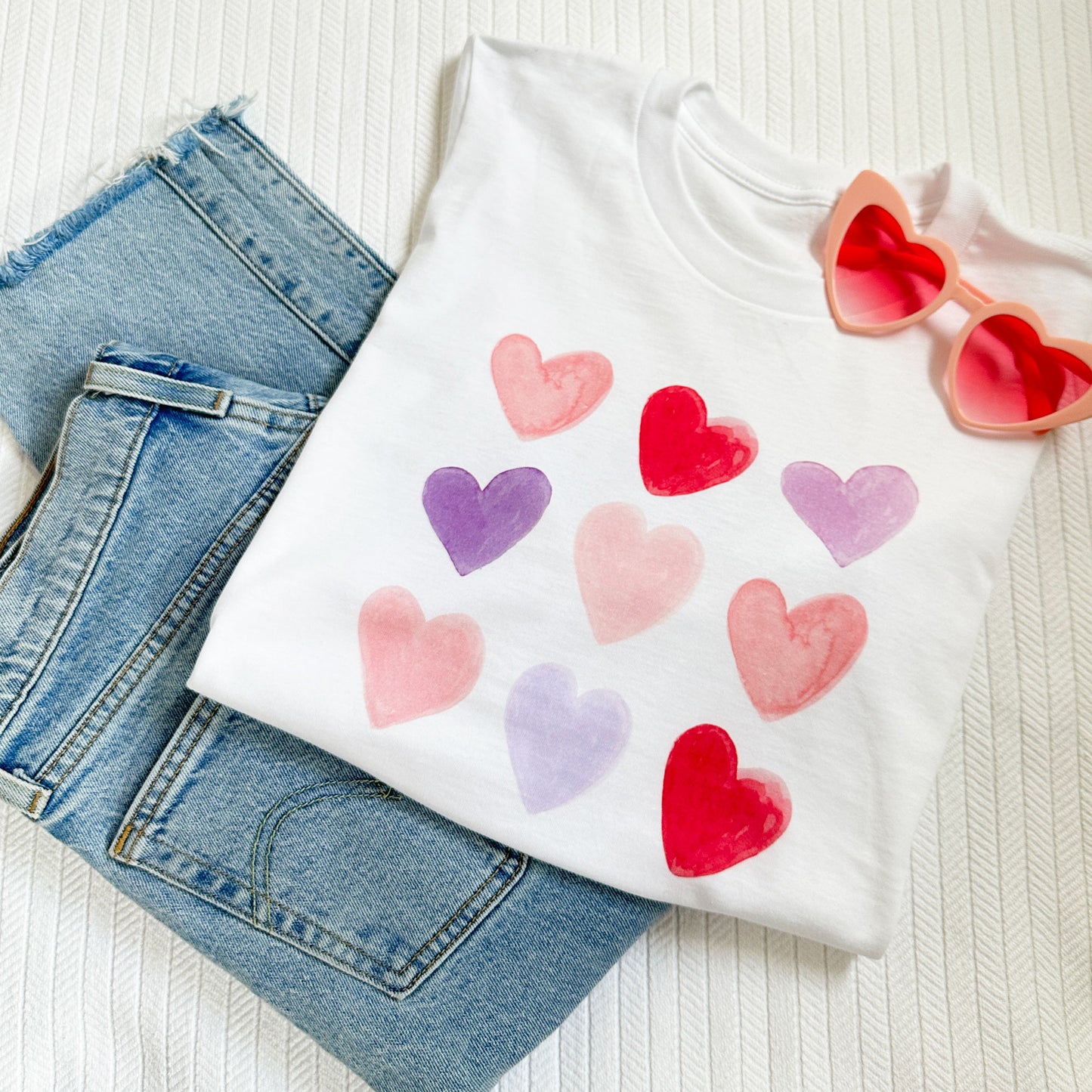 white t-shirt with a pink, red, and purple watercolor heart print in a 3X3 grid