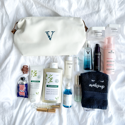 Our white cosmetic bag surrounded by a variety of toiletry items