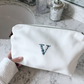 spacious white makeup travel bag with zipper closure, floral embroidered initial sitting on a bathroom counter
