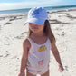 young girl playing on a beach with a white baseball cap with embroidered monogram in periwinkle thread