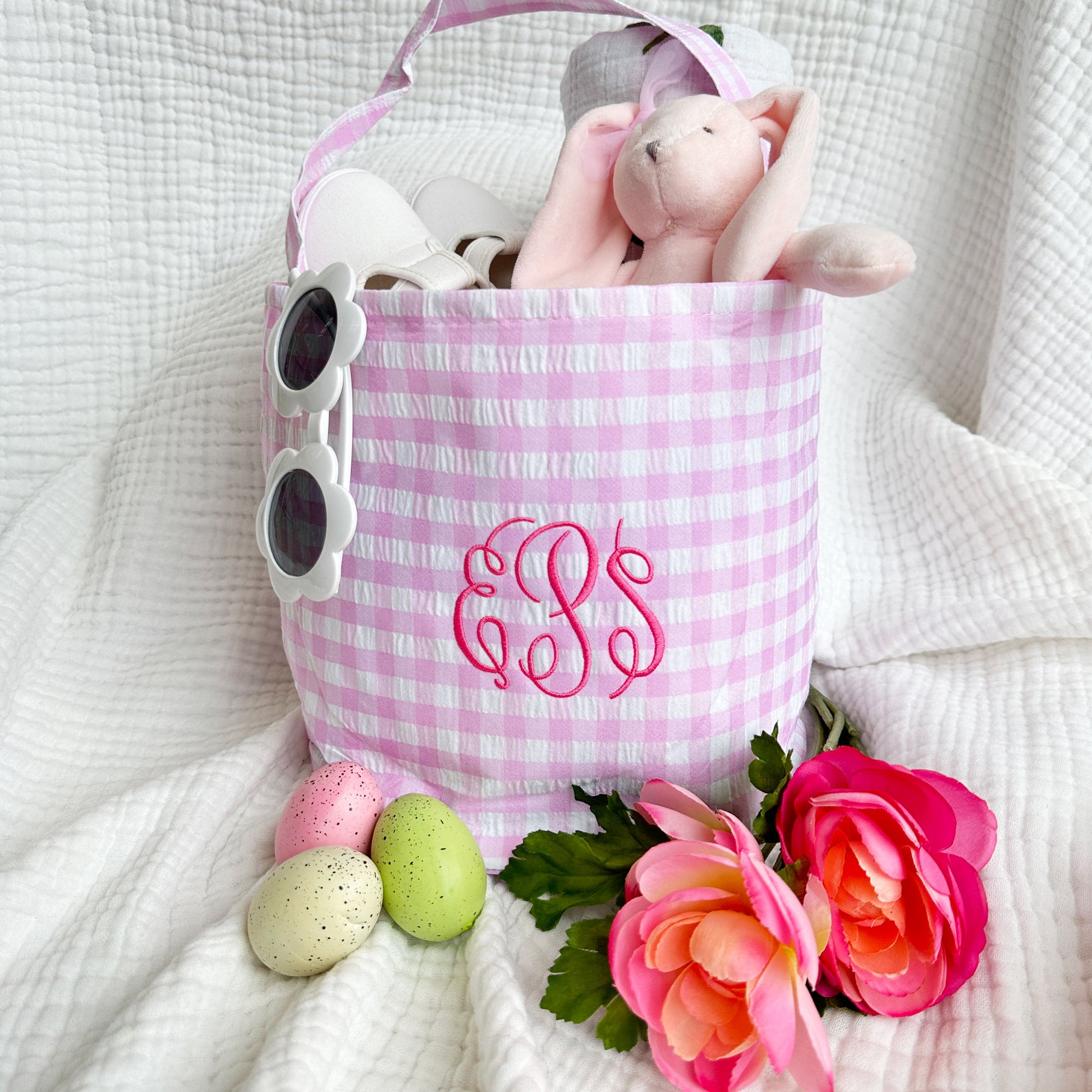 Pink gingham easter basket filled with gifts featuring a three letter cursive girly monogram embroidered in a darker pink thread