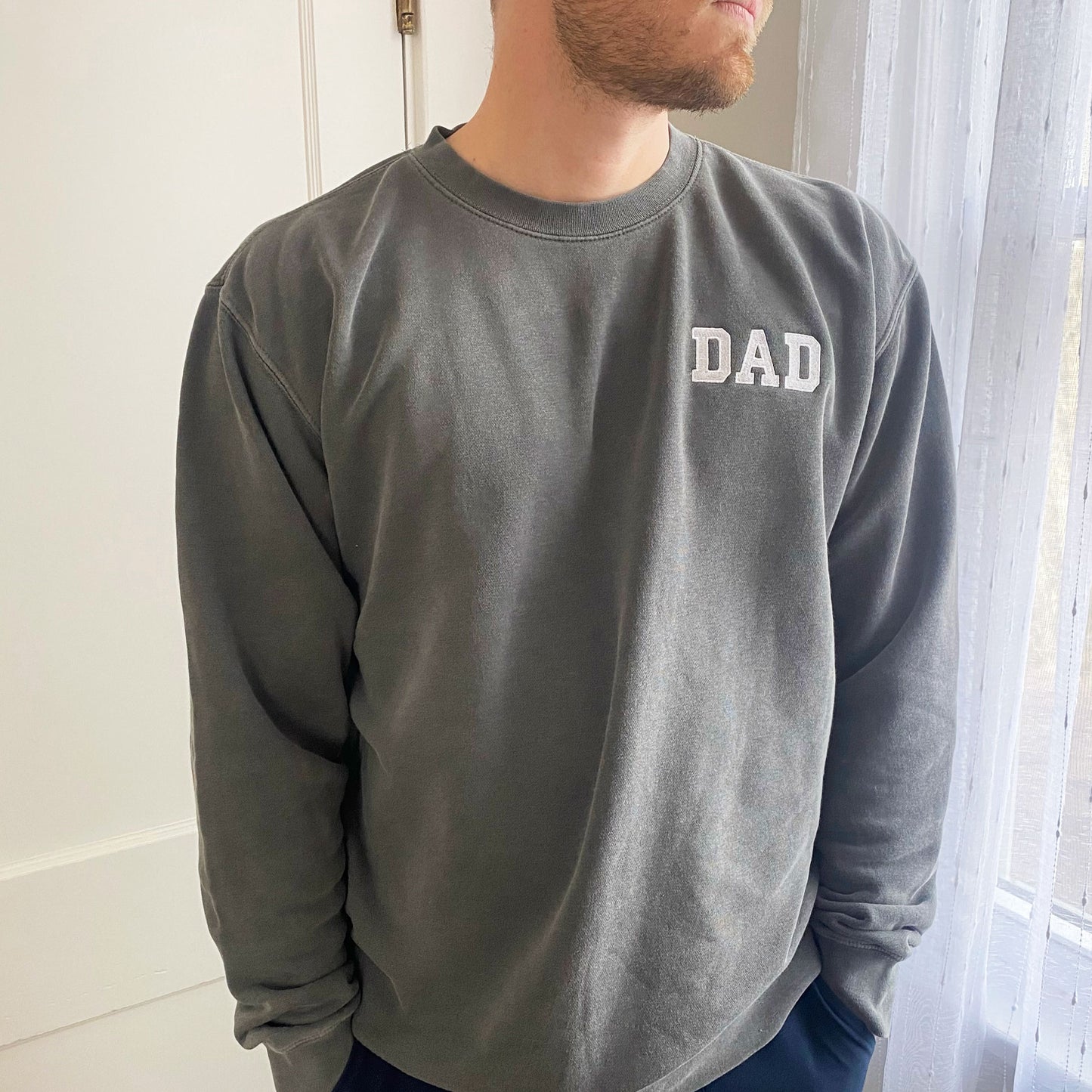 Man wearing pigment black sweatshirt with white dad embroidered text