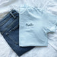 chambray comfort colors short sleeve tee with embroidered white tooth outline and name Maddie in a script font and French blue thread over the tooth styled with a jeans
